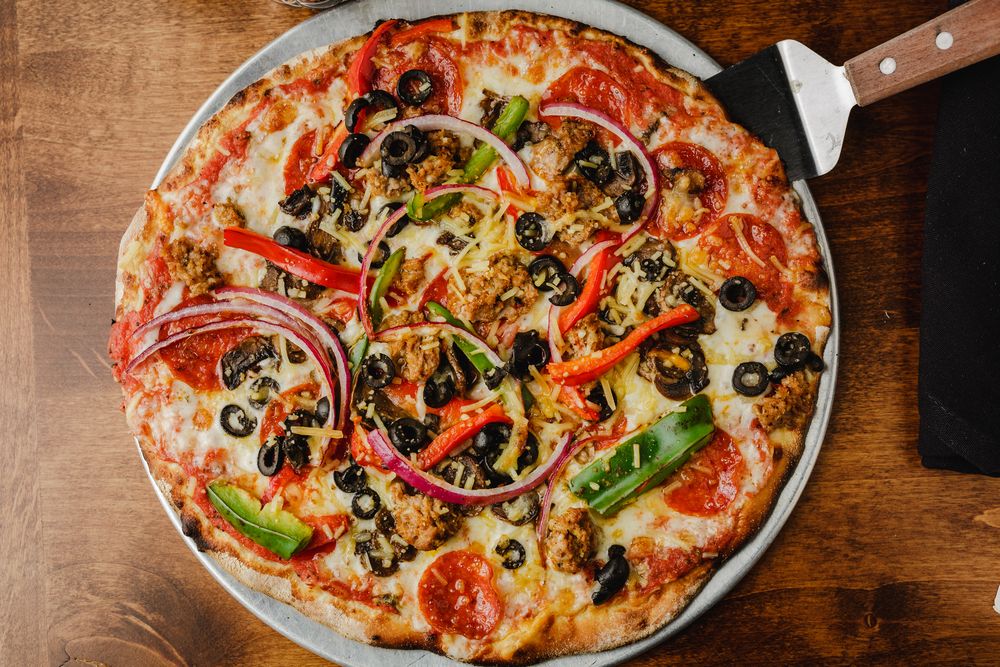 Wood-fired supreme pizza fresh from The Abbey's open kitchen